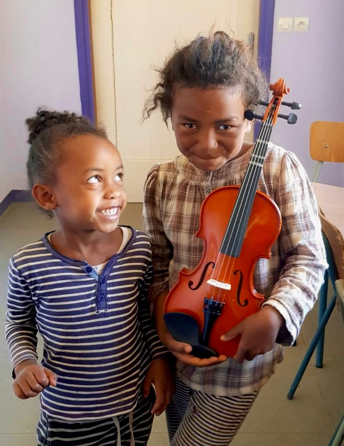 To children smiling, one with a violin