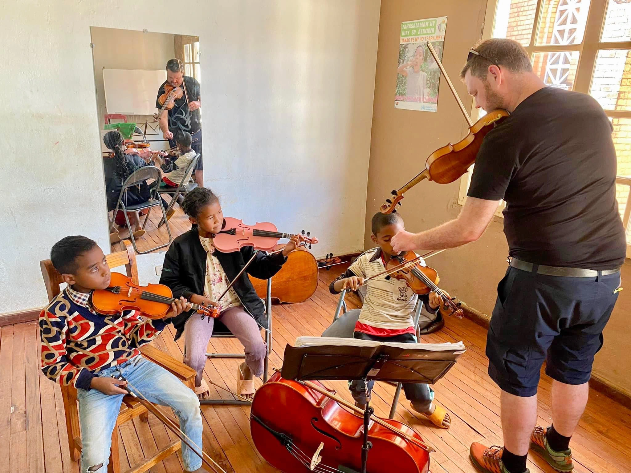 Teacher teaching three children violin